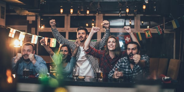 Fans an einer Bar jubeln auf einen Fernseher schauend